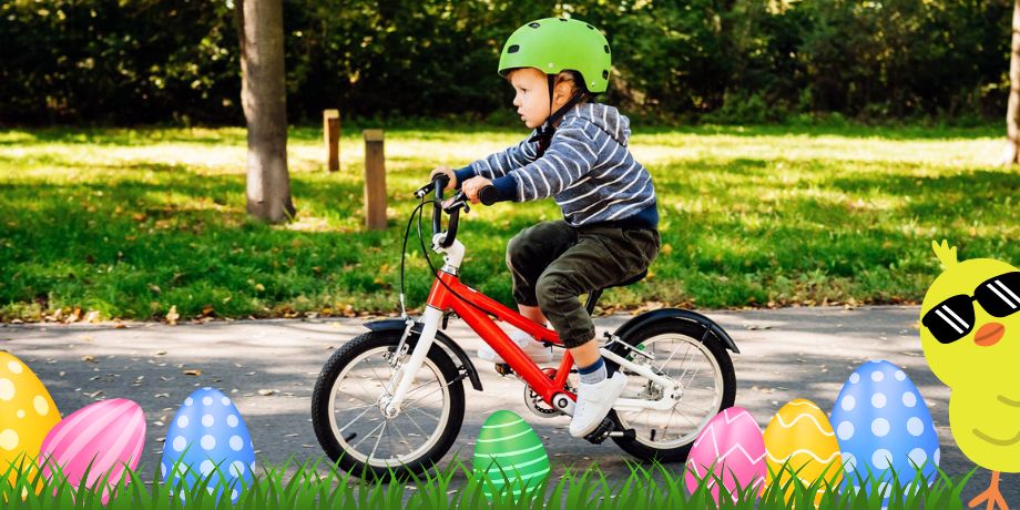 Egy kisfiú biciklizik a parkban, sisakban. A képen dekorációs húsvéti tojások vannak.
